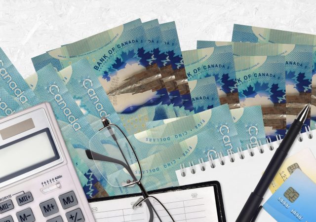 5 Canadian dollars bills and calculator with glasses and pen. Tax payment season concept or investment solutions. Financial planning or accountant paperwork SSUCv3H4sIAAAAAAAACpyRwW7DIAyG75P2DhHnRmoSqoa+SrWDQ9wGlUIFZNNU9d1nIFScd8Of7d/+zfPzo2nYBF5JdmqeMaJYab364CAoawjvdxt3aGZ0NcFZBesU6BpOEORi4I4Ezap1xK+UZD5AWD36OGxDEgJeSSPDt0Te6JzjpiRSkjooxdiuYn6dEisoi/+rMz++ihu4opG/aeHKiEONkI2ccym7/QR099oarLOylatvK0HHgqFSejgllblWbTYs6cqlTdrVBBdXeG/OtLUPmHQ88YU0sfAFvKfyufBqkKQ/tfdqjrEhGdhU2Uw/EcNu6AfRd8d+33MhDn3Pt4L8e4sinbROEaJY3tRcW1dxAyYOAvAy8vYixq7lcBjakSO2KPYjSA4cpyMd/vUHAAD//wMA5f6uoocCAAA=